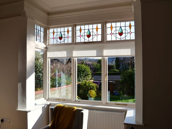 Photograph of a Dublin period home red brick facade featuring new white double glazed casement windows with stained glass and granite windows sills.