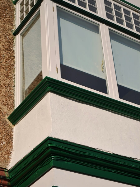 Close-up photograph of a Dublin period home red brick facade featuring new white double glazed casement windows with granite windows sills.