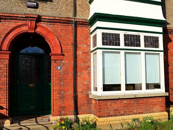 Photograph of a Dublin period home red brick facade featuring new white double glazed casement windows with granite windows sills.