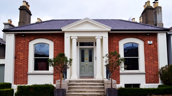 Exterior photograph of a period red brick facade home with white sash window and granite window sills.