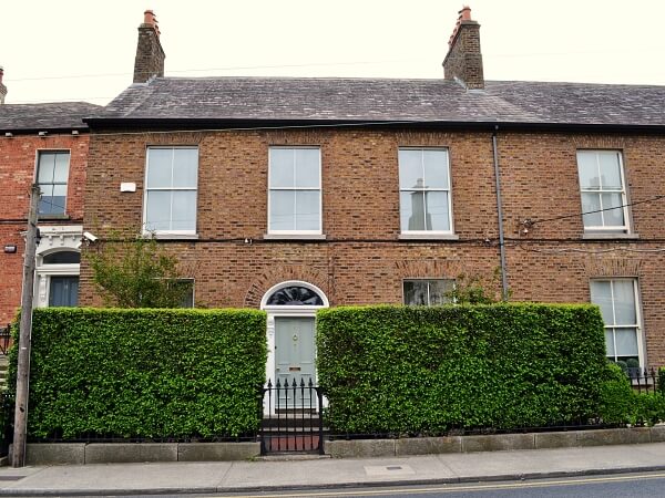 Close-up exterior photograph of a period brick facade home with white panelled sash window and granite window sills.