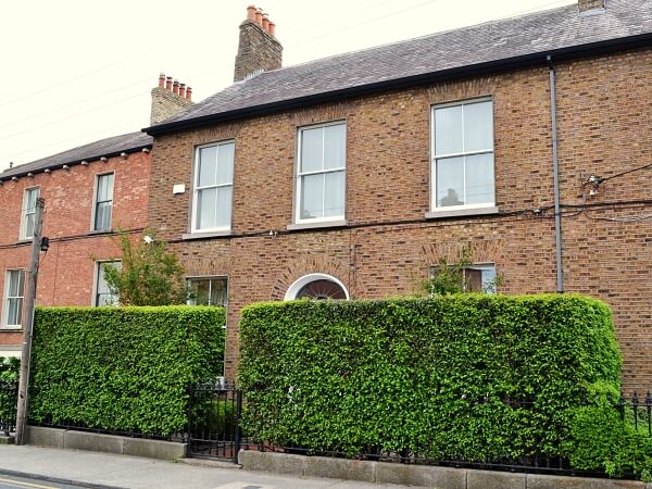 Close-up exterior photograph of a period brick facade home with white panelled sash window and granite window sills.