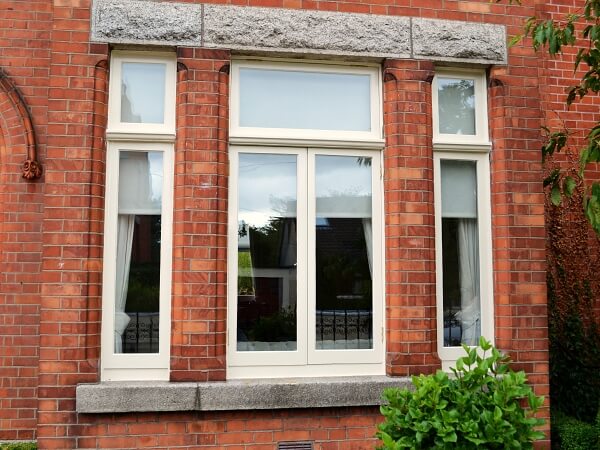 Photograph of a Dublin period home red brick facade featuring new white double glazed casement windows with granite windows sills.