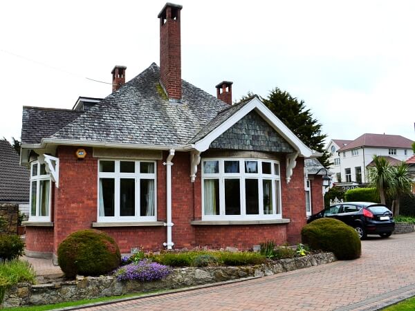 Photograph of a Dublin period home red brick facade featuring new white double glazed casement windows with granite windows sills.