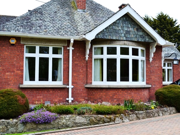 Photograph of a Dublin period home red brick facade featuring new white double glazed casement windows with granite windows sills.