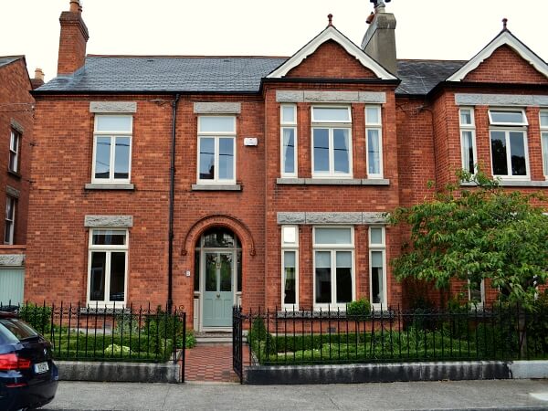 Photograph of a Dublin period home red brick facade featuring new white double glazed casement windows with granite windows sills.