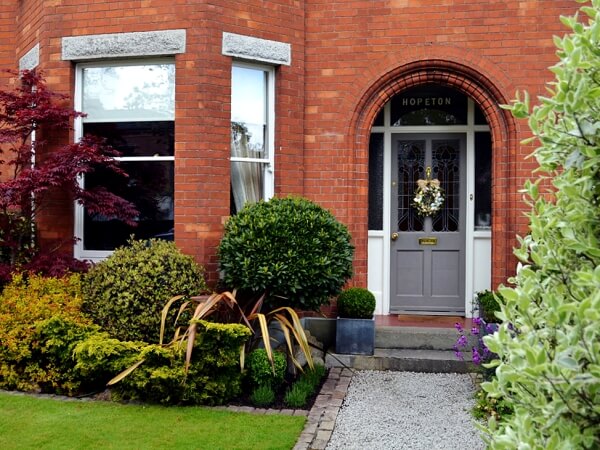 Close-up exterior photograph of a period red brick facade home with white sash window, period front door, granite steps and window sills.