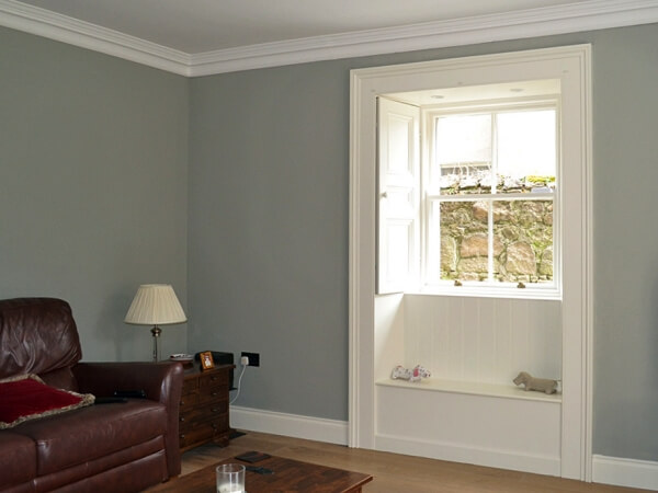 Close-up photograph of a period white panelled sash window with period window shutter and architrave.